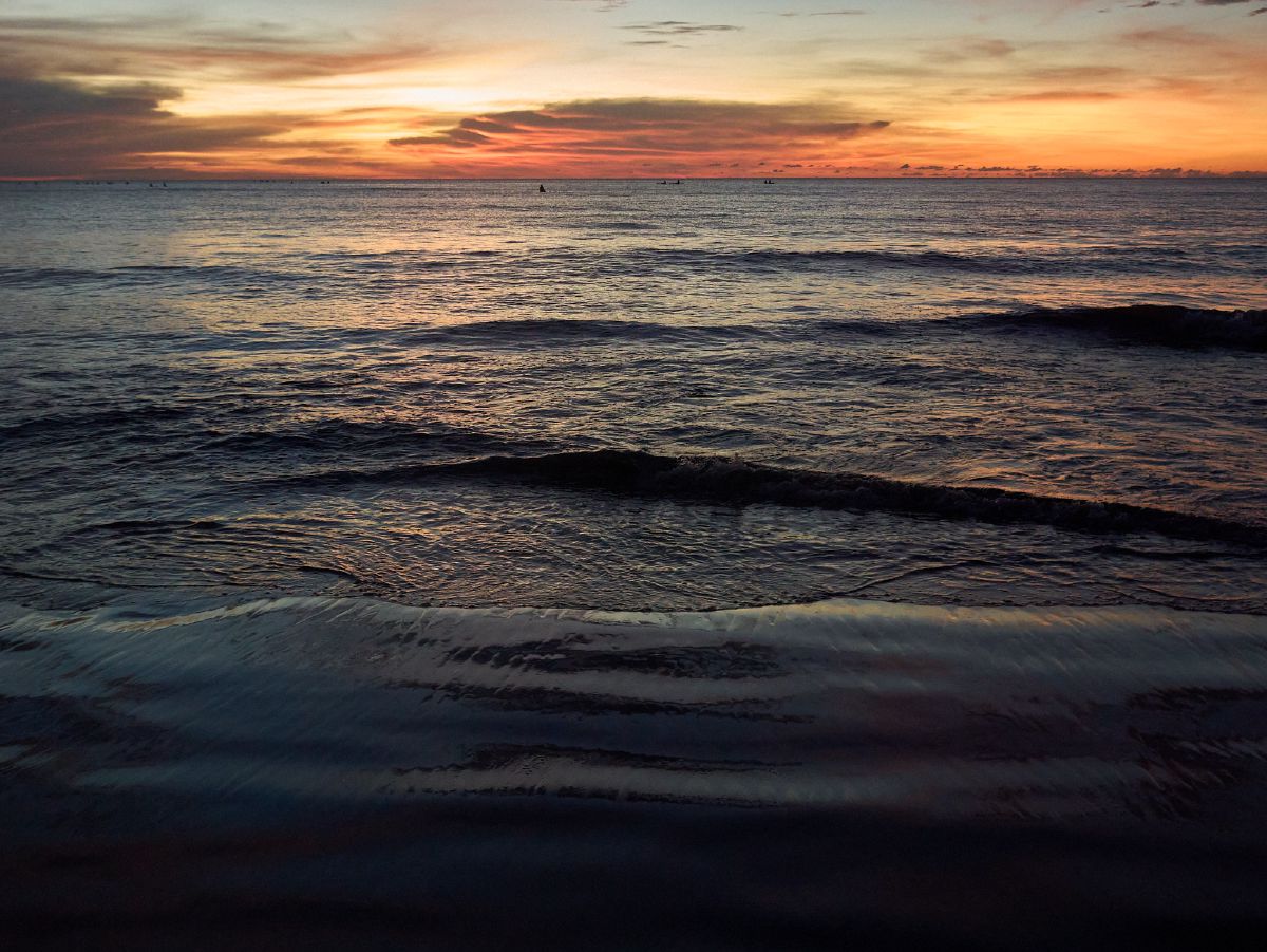 Golden sunset casting warm hues across gentle ocean waves at Kota Kinabalu.